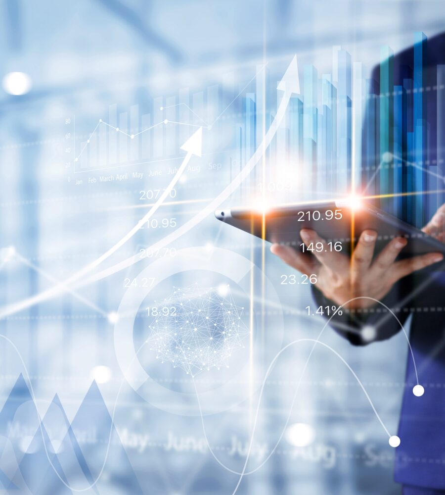 eschäftsperson im Anzug bedient ein Tablet, im Hintergrund sind digitale Finanzdiagramme und Wachstumskennzahlen zu sehen.